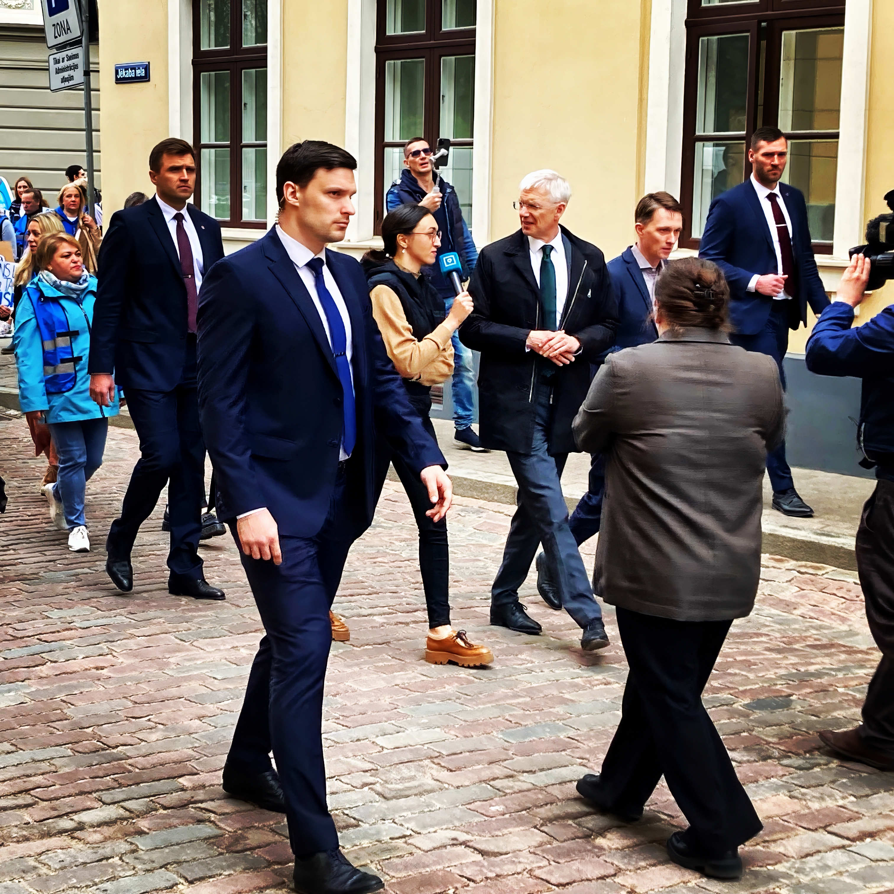 Mielenosoitustilanne: poliitikko ja yleisö banderollien ja valon rajapinnassa.